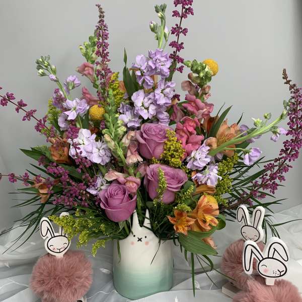 Mixed pink and purple bouquet in a ceramic vase with bunny decorations