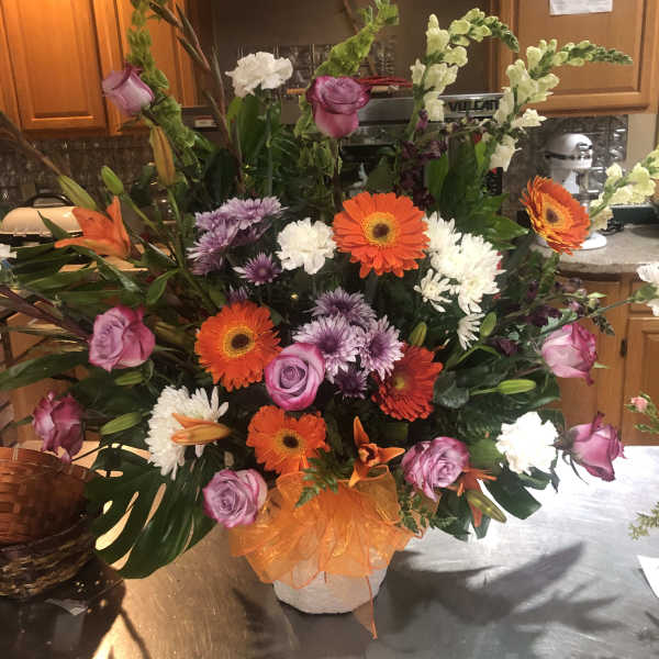Large mixed bouquet in a white vase with orange ribbon