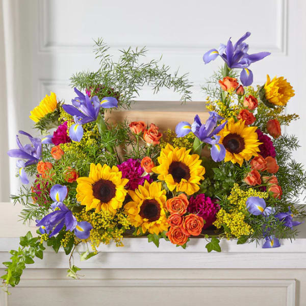 Bright mixed flower arrangement with sunflowers, purple irises, and orange roses