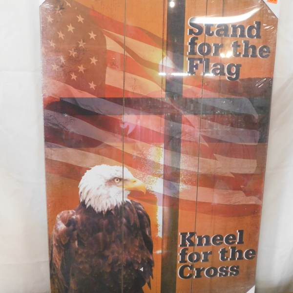 Decorative sign with an American flag and eagle, reading "Stand for the Flag" and "Kneel for the Cross".