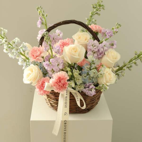 Basket of cream roses and pastel flowers with a ribbon