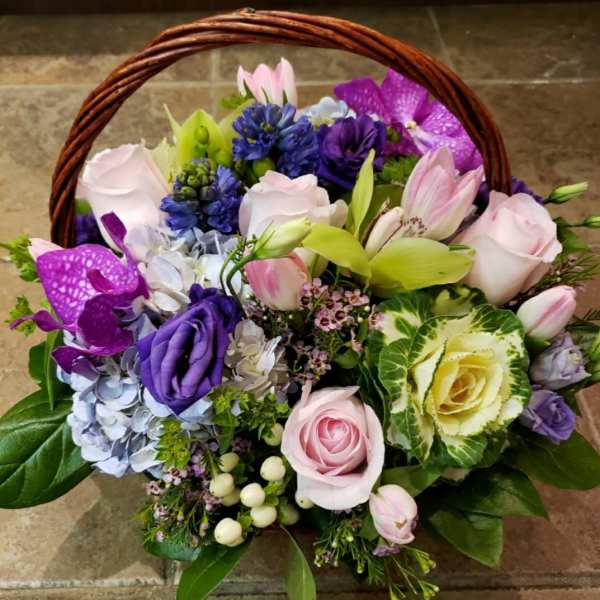 Basket of pink, purple, and blue flowers with roses and lilies