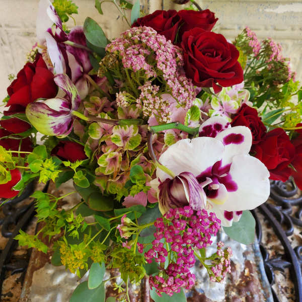 Bouquet of red roses and white-purple orchids with pink filler flowers