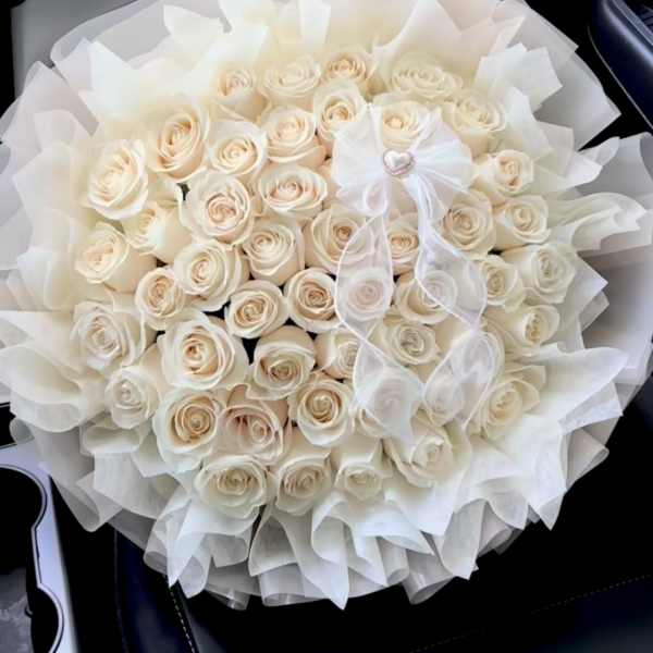 Round bouquet of cream roses wrapped in white tissue paper