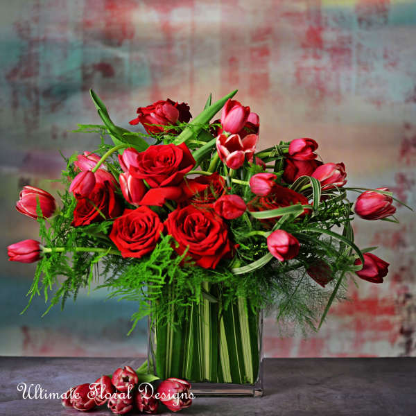 Red roses and pink tulips arranged in a clear square vase