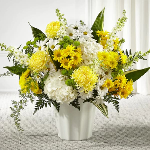 Yellow and white mixed flower arrangement in a white vase