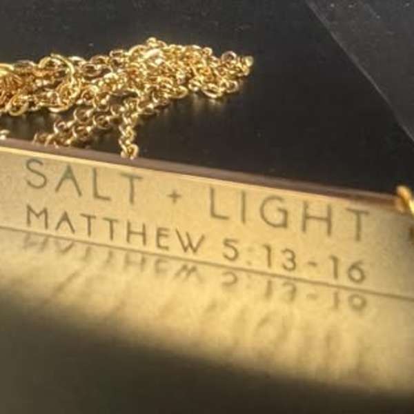 Gold necklace with a rectangular pendant engraved "SALT + LIGHT"