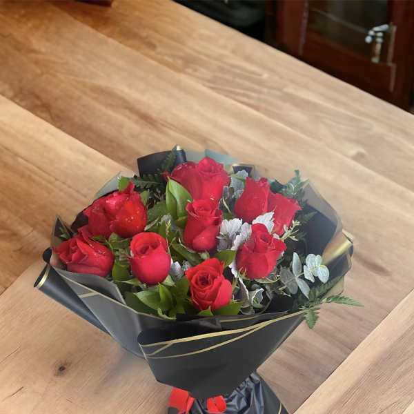 Bouquet of red roses wrapped in black paper with gold trim