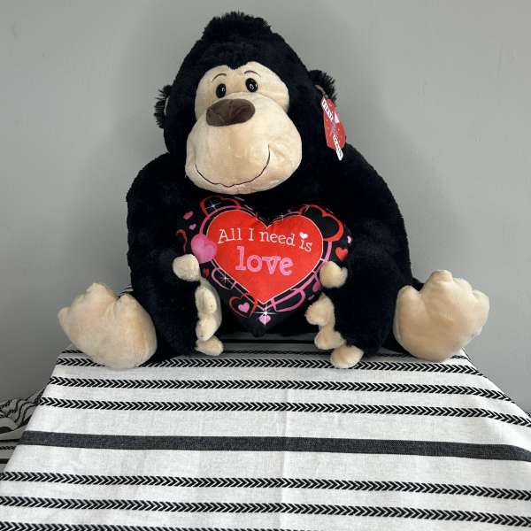 Plush gorilla holding a heart that says "All I need is love"
