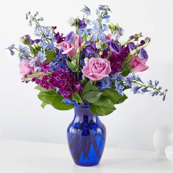 Pink roses and purple-blue flowers in a cobalt glass vase
