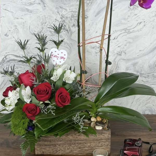 Purple orchids and red roses in a wooden box with a heart pick