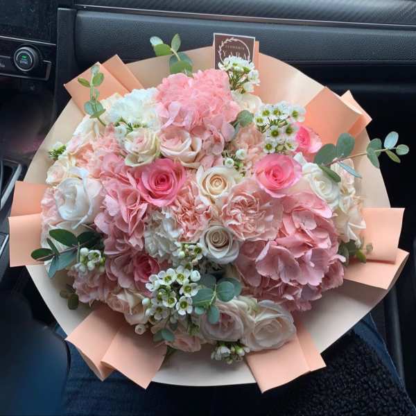 Bouquet of pink and white roses with hydrangeas and eucalyptus in peach wrap
