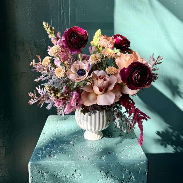 Mixed pink and peach flowers arranged in a white vase