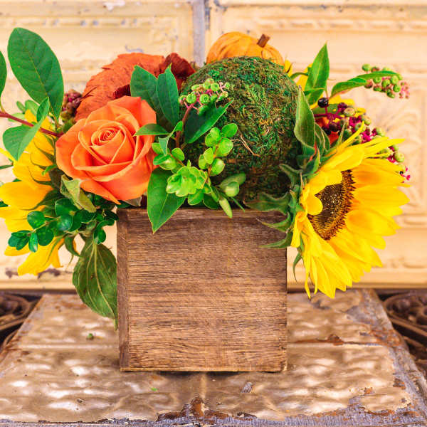 Orange rose and sunflowers in a wooden box with greenery