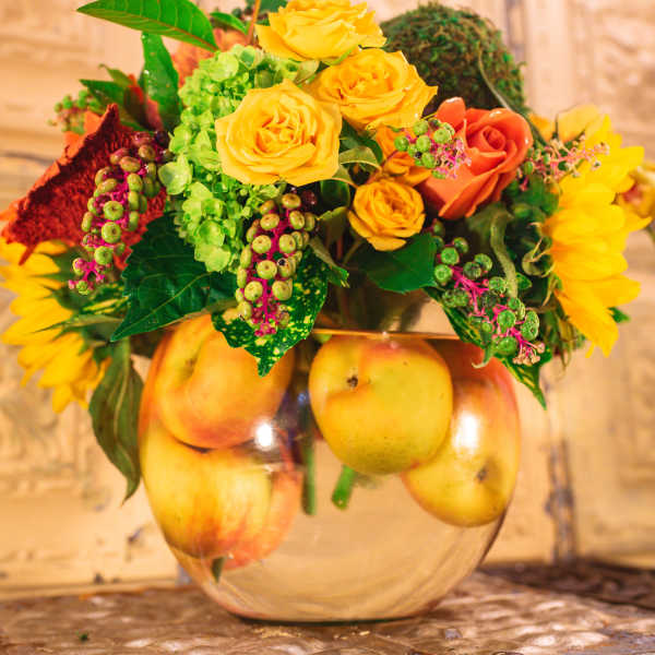 Yellow and orange roses in a glass bowl with apples