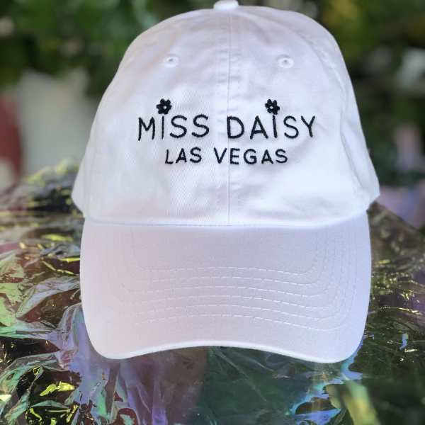 White baseball cap embroidered with "MISS DAISY LAS VEGAS"