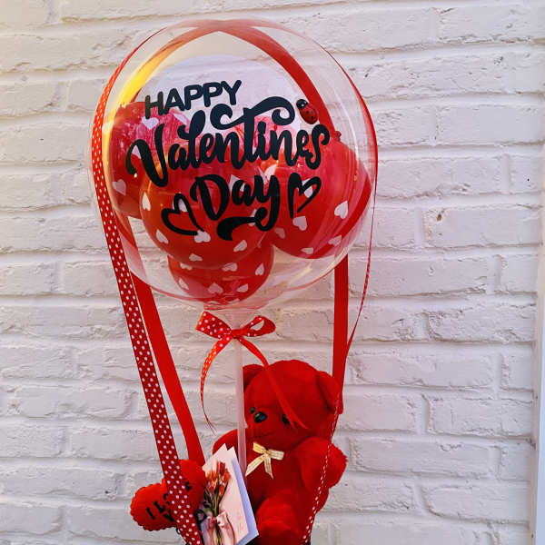 Valentine's Day balloon arrangement with a red teddy bear in a black basket