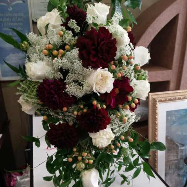 Tall bouquet of white and burgundy flowers with trailing greenery