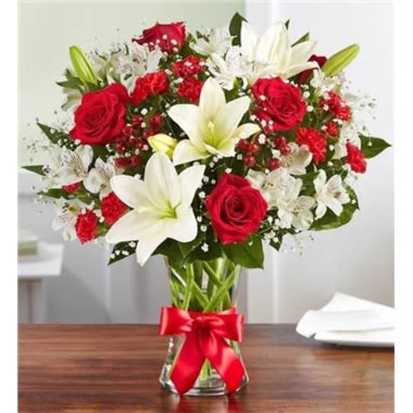 Bouquet of red roses and white lilies in a glass vase with a red ribbon