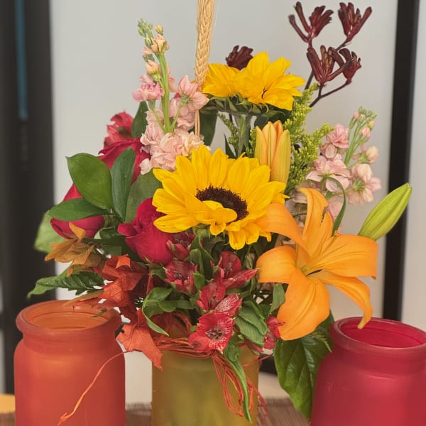 Mixed bouquet with sunflowers, lilies, roses, and pink filler flowers in a vase