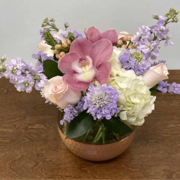 Pink orchid and pastel flowers in a copper bowl vase