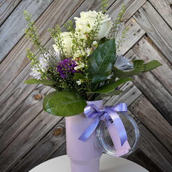 White and purple bouquet in a lavender tumbler with a ribbon