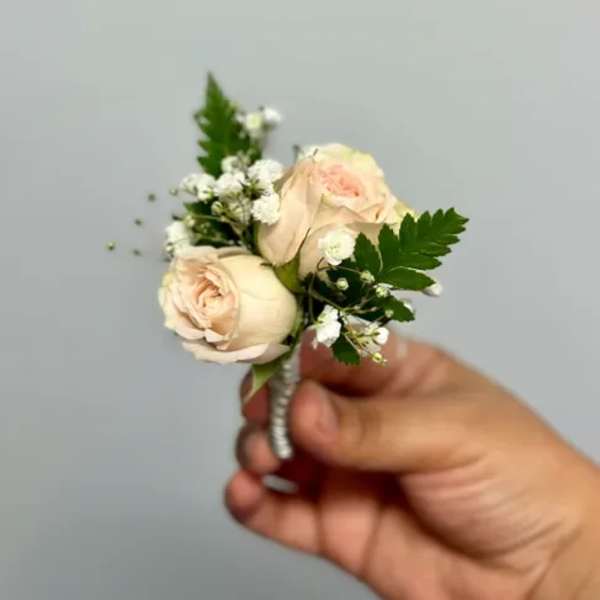 Small cream rose boutonniere with white filler flowers and greenery