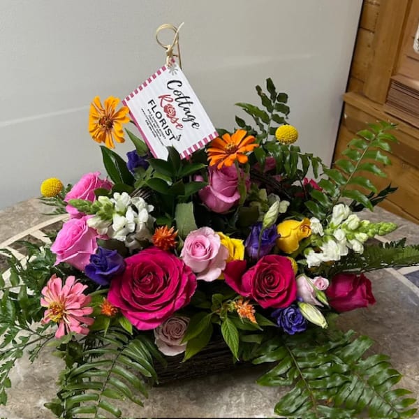 Mixed bouquet of roses, daisies, and snapdragons in a basket