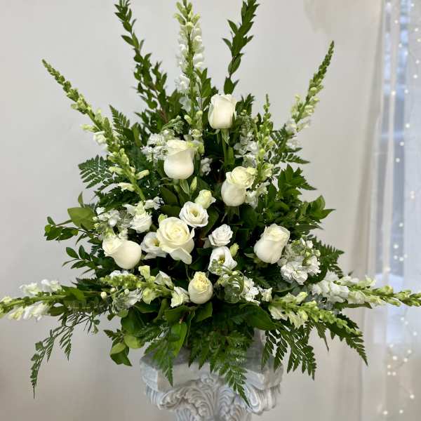 Tall white rose and snapdragon arrangement in a white pedestal urn