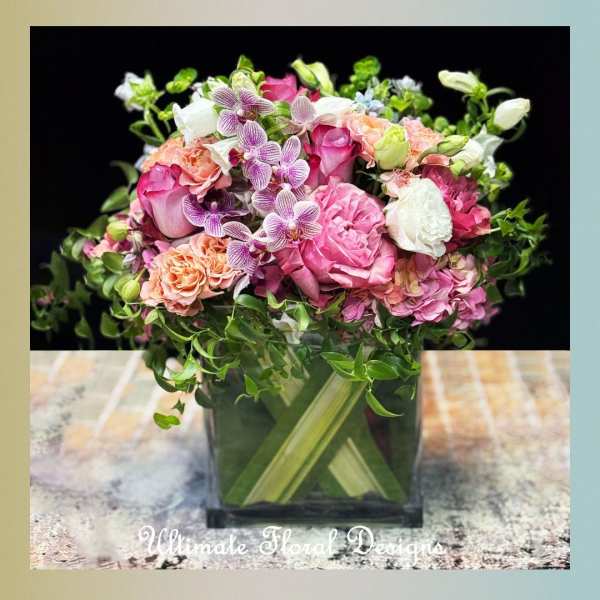 Pink and white floral arrangement in a square glass vase
