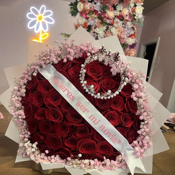 Heart-shaped bouquet of red roses with pink baby's breath and a pearl crown