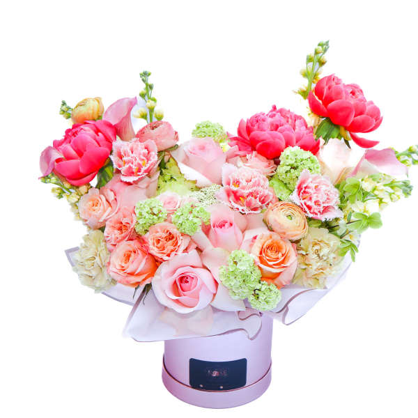 Bouquet of pink and peach flowers in a round hatbox