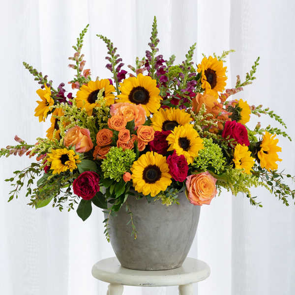Mixed bouquet of sunflowers and roses in a gray vase