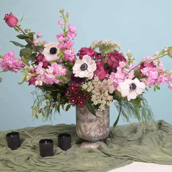Pink and white floral arrangement in a ceramic vase with three black candles