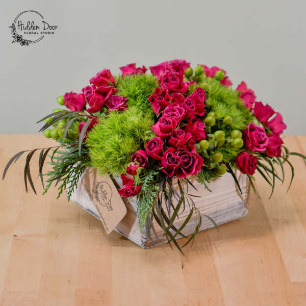 Pink roses and green pom-pom flowers in a rustic wooden box