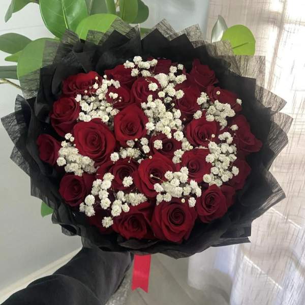 Bouquet of red roses with white baby's breath wrapped in black paper