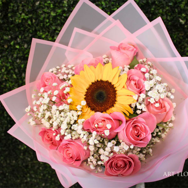Pink rose bouquet with a sunflower and baby's breath wrapped in pink paper
