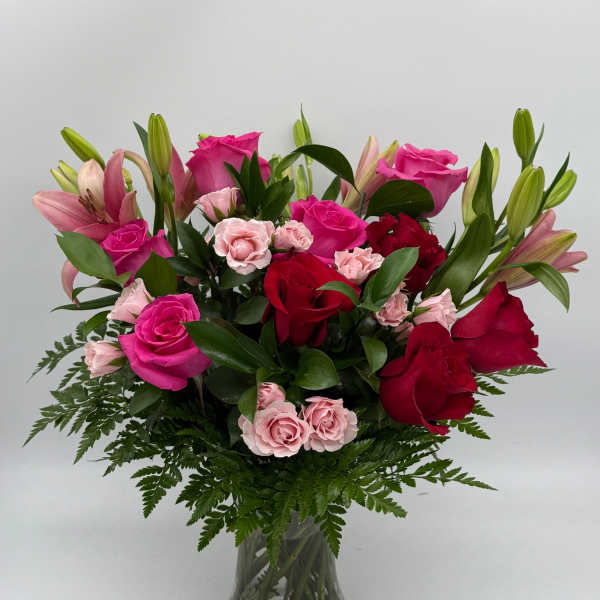 Pink and red roses with lilies in a glass vase