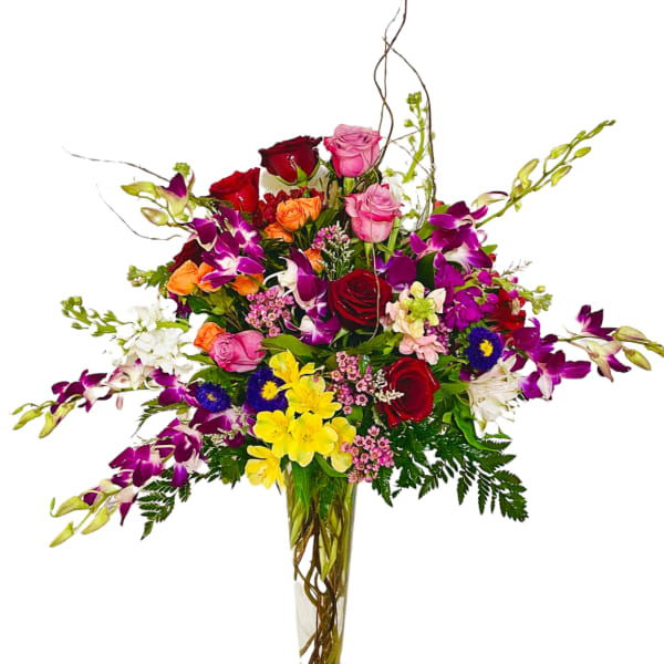 Tall mixed bouquet in a clear glass vase with roses and orchids
