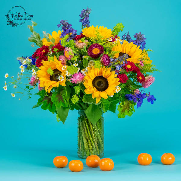 Colorful bouquet of sunflowers and mixed blooms in a glass jar vase