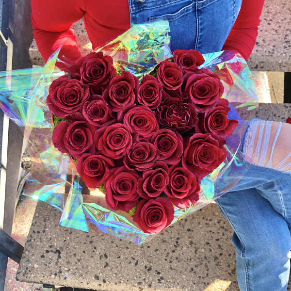 Heart-shaped bouquet of red roses wrapped in iridescent paper