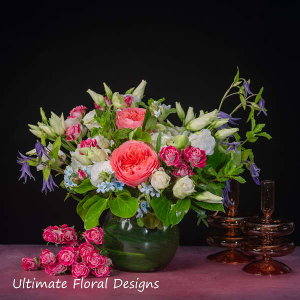 Mixed pink, white, and purple floral arrangement in a dark glass vase
