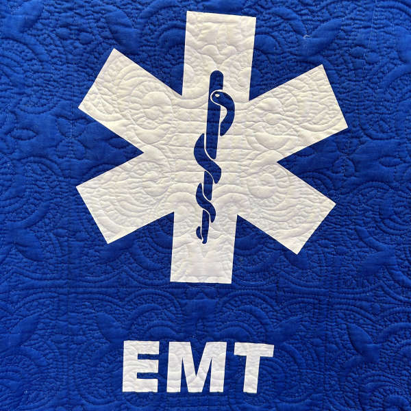 Blue quilted fabric with a white EMT medical symbol and text