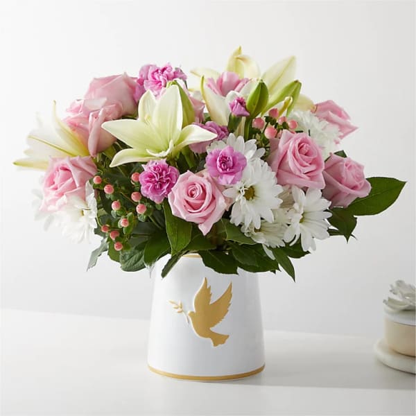 Pink roses and white lilies in a white vase with a gold dove