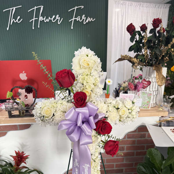 Cross-shaped floral tribute with red and white roses and a lavender ribbon