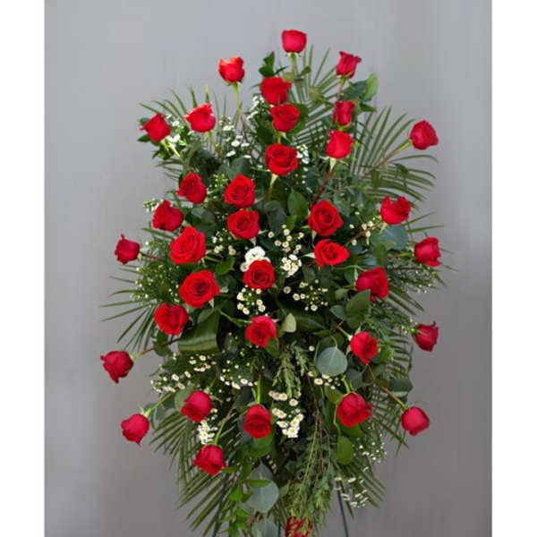 Standing spray of red roses with greenery on a metal easel