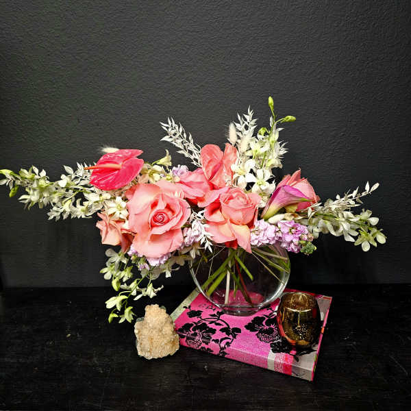 Pink roses and white orchids arranged in a clear glass vase