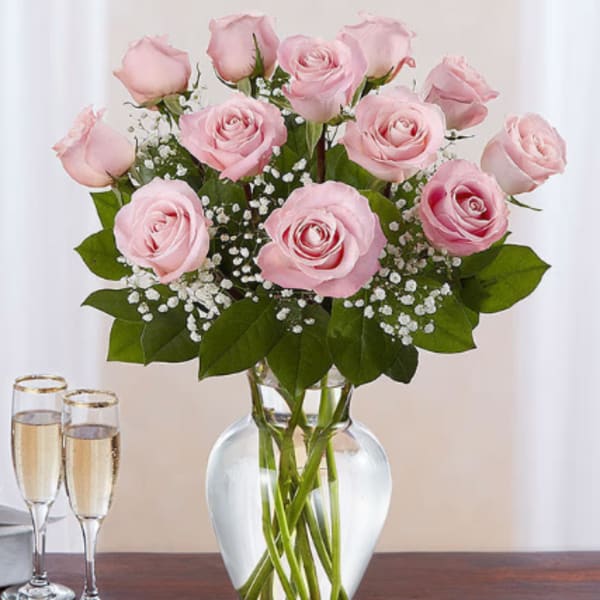 Pink roses arranged in a clear glass vase with baby's breath
