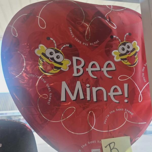 Red heart-shaped balloon with cartoon bees and the words "Bee Mine!"