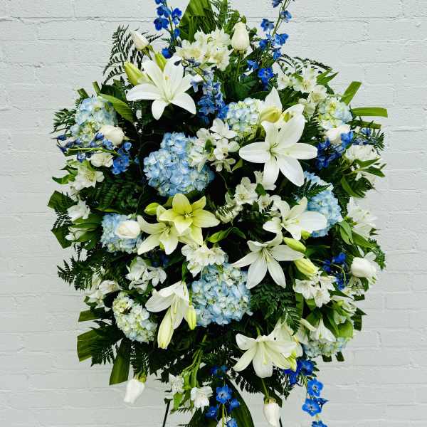 Large standing floral spray with white lilies, blue flowers, and hydrangeas